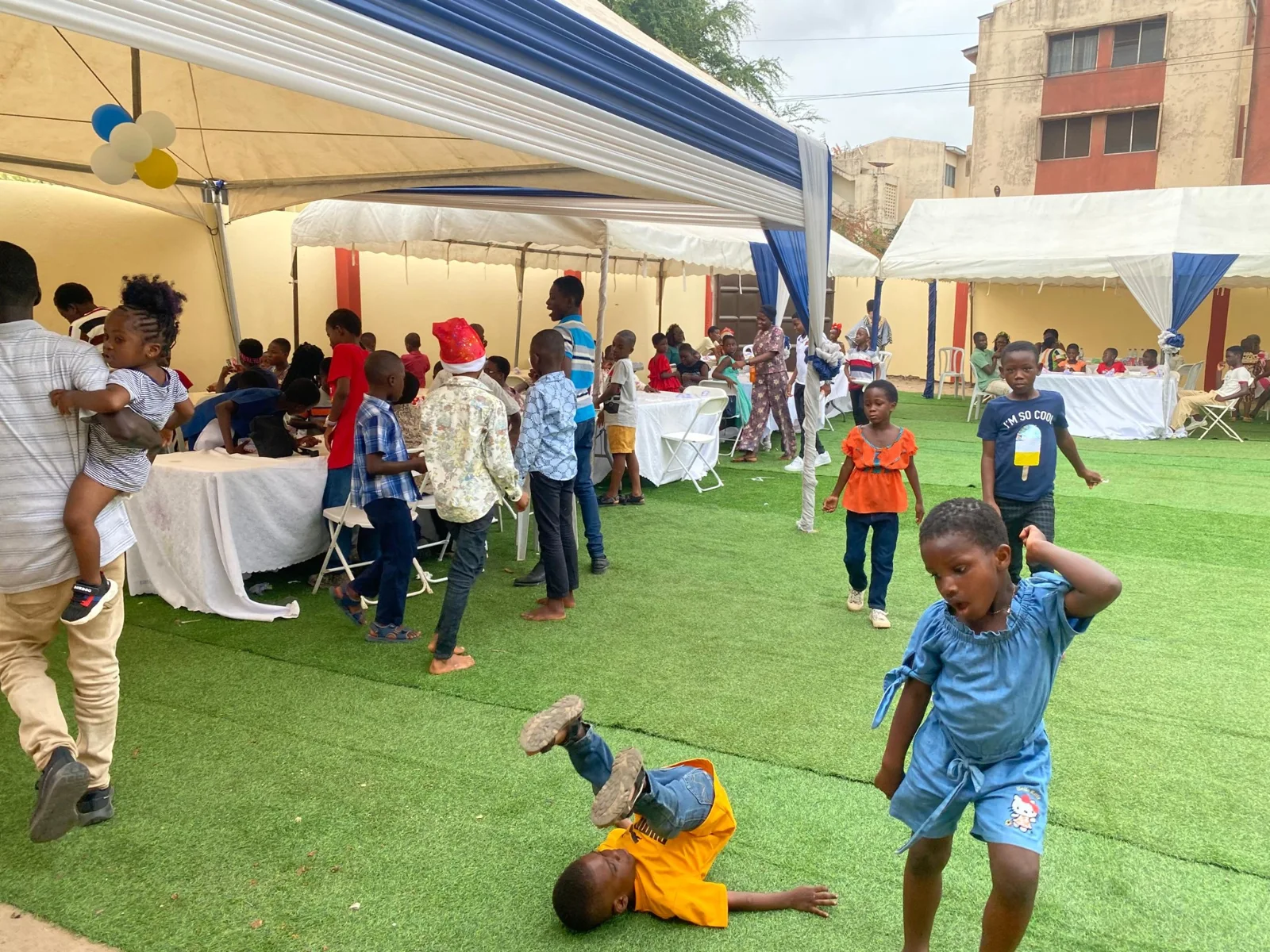 Children enjoying games on the lawn beside event canopies.