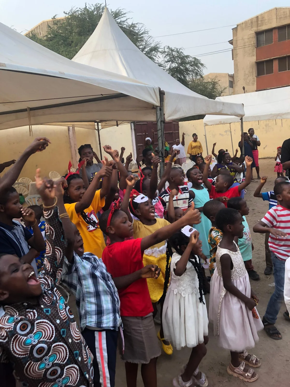 A large group of children and adults celebrating together outdoors.